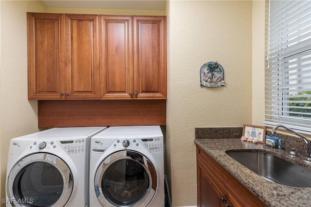 washroom with cabinets, sink, and washer and clothes dryer