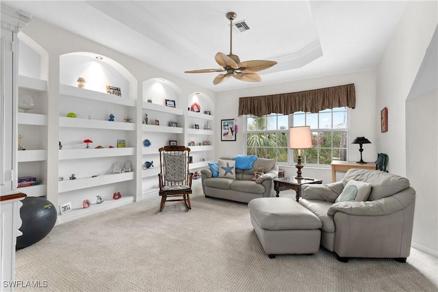 carpeted living room featuring ceiling fan, a tray ceiling, and built in features