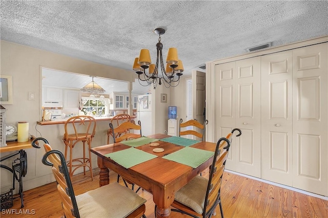 6253 Valeria Rd, Bokeelia, FL 33922 - dining space featuring a textured ceiling, light hardwood / wood-style flooring, and an inviting chandelier