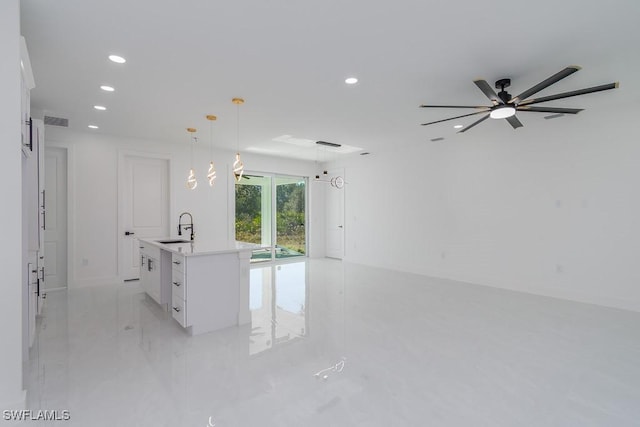 kitchen with ceiling fan, sink, pendant lighting, a center island with sink, and white cabinets