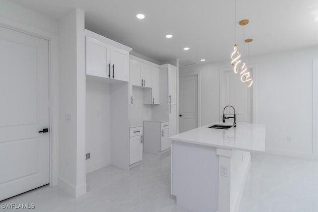 kitchen featuring white cabinetry, sink, an island with sink, and pendant lighting