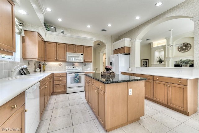 kitchen with white appliances, a center island, ceiling fan, decorative backsplash, and sink