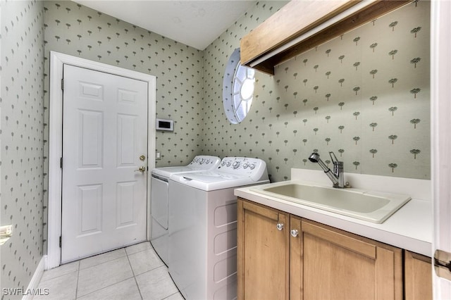 laundry room featuring sink, washing machine and dryer, light tile patterned floors, and cabinets