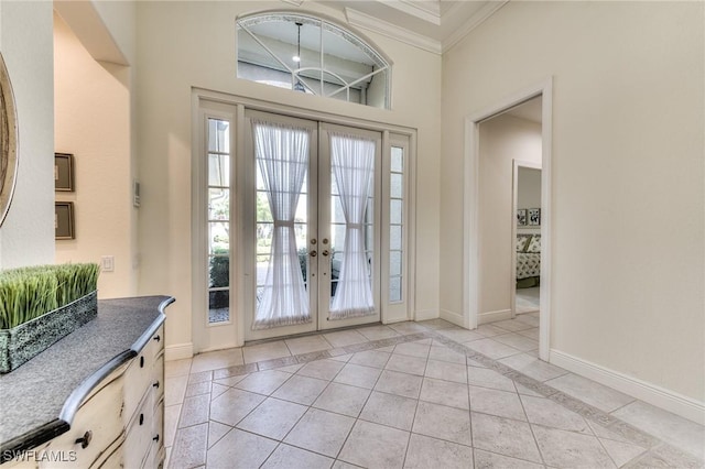 foyer entrance with ornamental molding, french doors, and light tile patterned floors