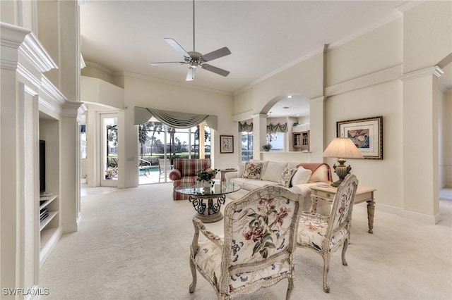 carpeted living room with a high ceiling, ceiling fan, ornamental molding, and decorative columns