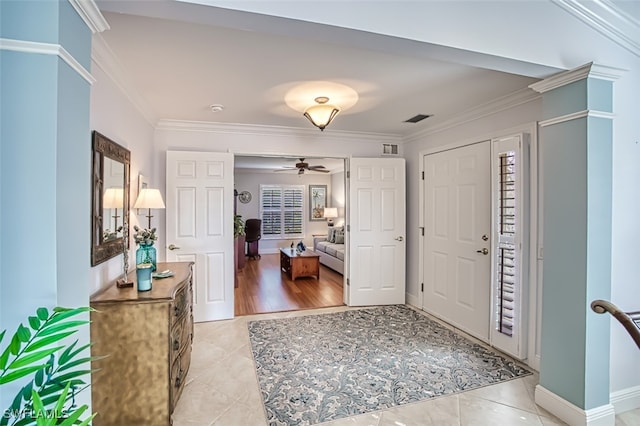 tiled foyer entrance featuring ceiling fan and ornamental molding