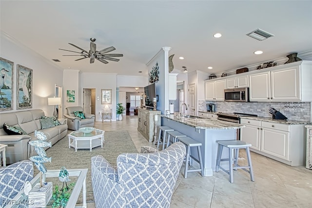 kitchen featuring white cabinets, backsplash, appliances with stainless steel finishes, and a breakfast bar