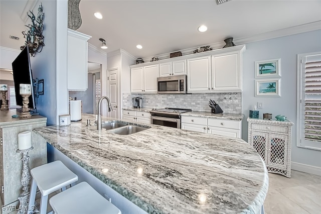 kitchen featuring light stone counters, sink, white cabinetry, and appliances with stainless steel finishes