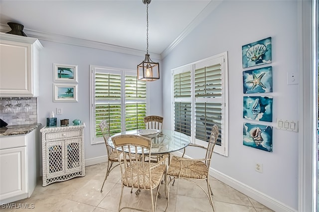 tiled dining room featuring ornamental molding and vaulted ceiling