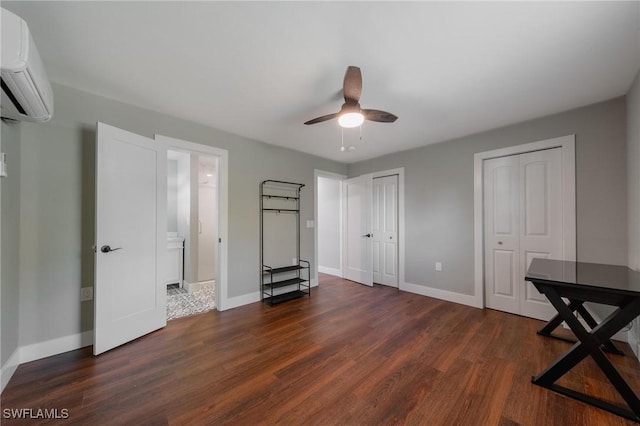 unfurnished bedroom with an AC wall unit, ceiling fan, dark hardwood / wood-style flooring, and two closets