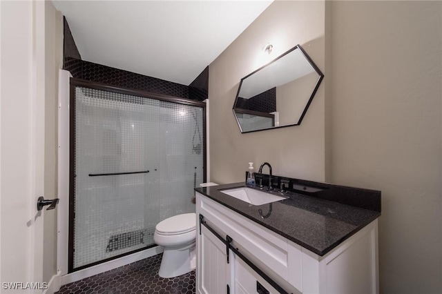 bathroom with tile patterned flooring, a shower with door, vanity, and toilet