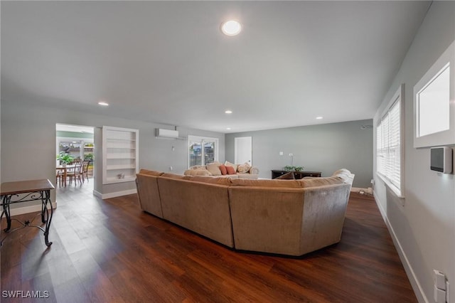 living room with a wall unit AC, dark hardwood / wood-style flooring, and built in features