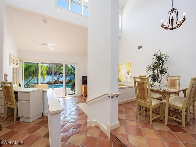 dining space with a high ceiling, ceiling fan with notable chandelier, and light tile patterned floors