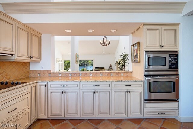 kitchen with tasteful backsplash, a notable chandelier, stainless steel appliances, and cream cabinetry