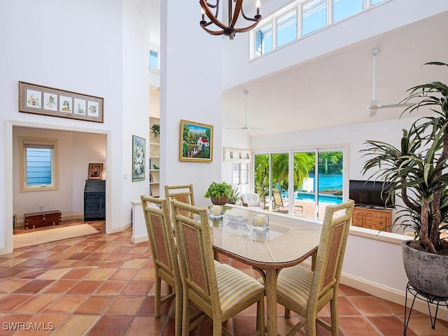 tiled dining area with a high ceiling and ceiling fan with notable chandelier