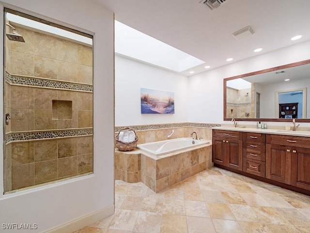 bathroom with vanity, a relaxing tiled tub, and a skylight