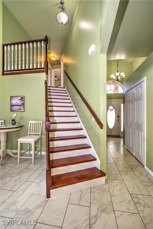 stairway featuring an inviting chandelier and a high ceiling