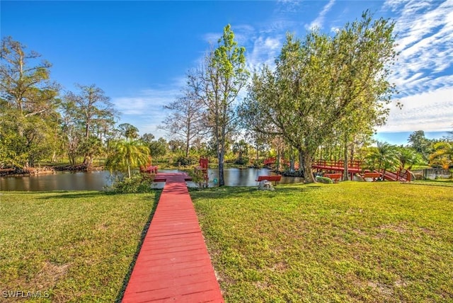 view of dock with a lawn and a water view