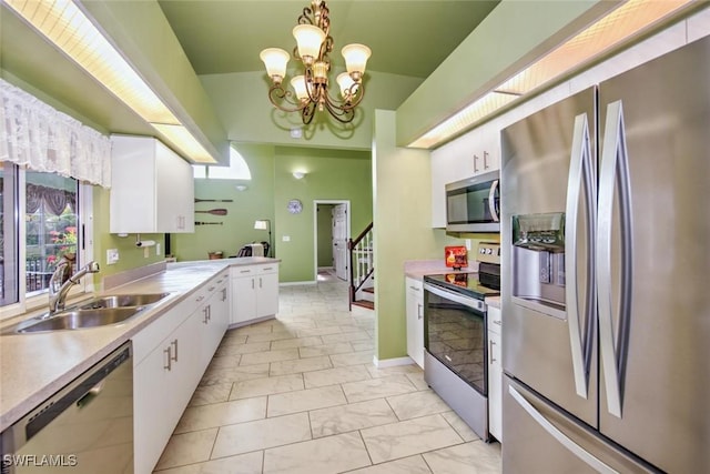 kitchen with appliances with stainless steel finishes, pendant lighting, white cabinetry, sink, and a notable chandelier