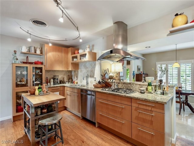 kitchen featuring stainless steel appliances, sink, butcher block counters, island exhaust hood, and decorative backsplash