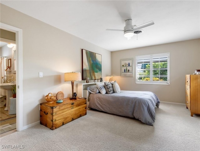 bedroom with ensuite bath, light colored carpet, and ceiling fan