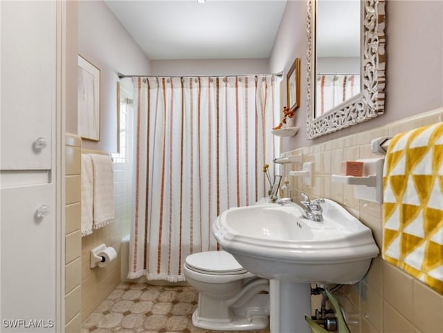 bathroom featuring tile walls, shower / bathtub combination with curtain, and toilet