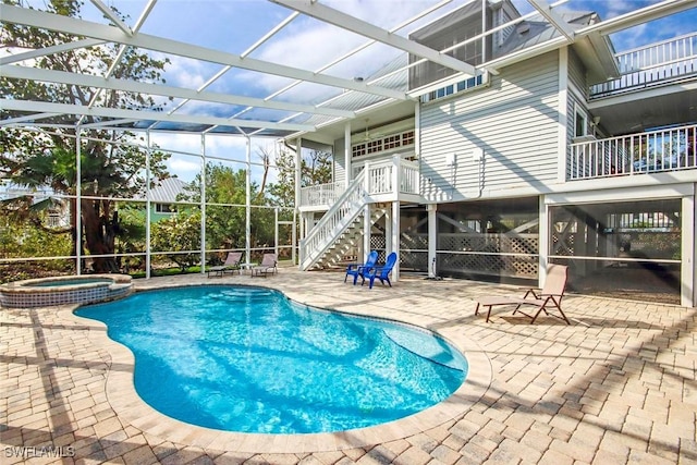 view of swimming pool featuring glass enclosure, a patio area, and an in ground hot tub