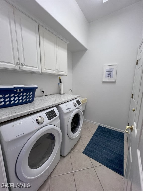 laundry room with washing machine and dryer, light tile patterned floors, and cabinets