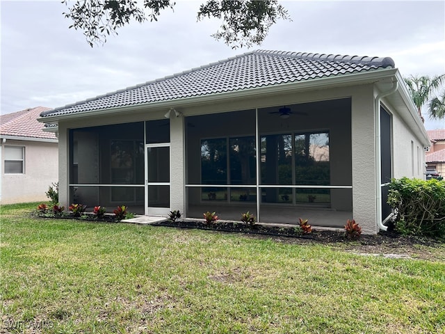 rear view of house featuring ceiling fan, a sunroom, and a lawn