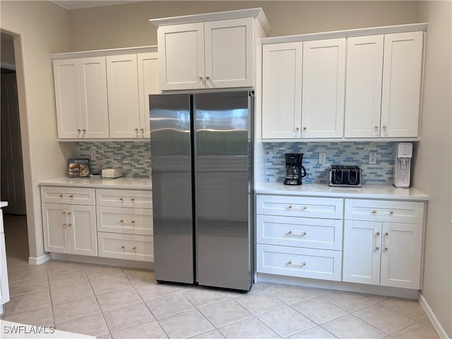 kitchen with white cabinets, light tile patterned floors, decorative backsplash, and stainless steel refrigerator