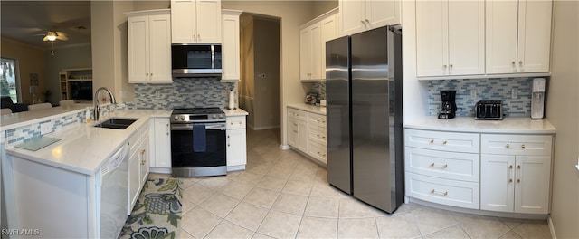 kitchen with stainless steel appliances, sink, white cabinets, light tile patterned floors, and backsplash