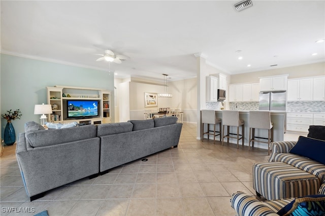 tiled living room featuring ornamental molding and ceiling fan