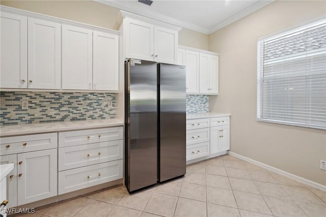 kitchen with stainless steel refrigerator, white cabinetry, crown molding, and light tile patterned flooring