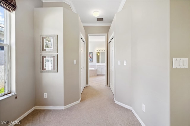 hall with ornamental molding and light carpet