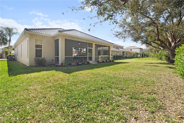 rear view of property featuring central AC unit and a lawn