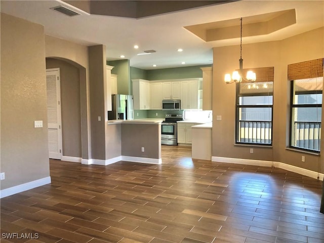 kitchen featuring pendant lighting, white cabinets, a notable chandelier, kitchen peninsula, and stainless steel appliances