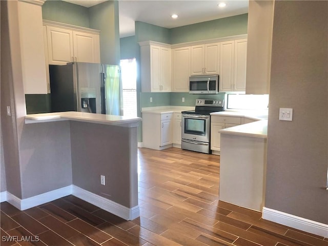 kitchen with white cabinetry, baseboards, wood tiled floor, and appliances with stainless steel finishes