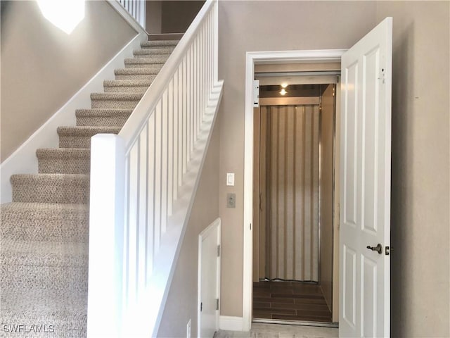 staircase featuring baseboards and wood finished floors