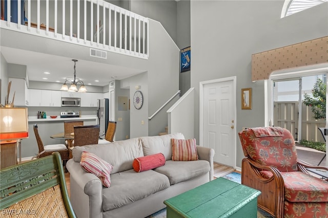 living room featuring wood-type flooring, a high ceiling, and a notable chandelier