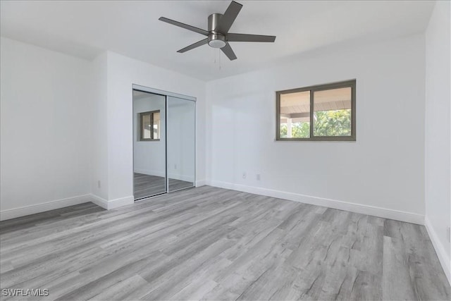 unfurnished bedroom featuring ceiling fan, a closet, and light wood-type flooring