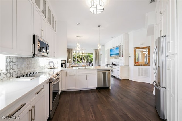 kitchen with appliances with stainless steel finishes, backsplash, white cabinets, dark hardwood / wood-style floors, and hanging light fixtures