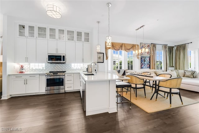 kitchen with pendant lighting, a breakfast bar, white cabinets, sink, and stainless steel appliances