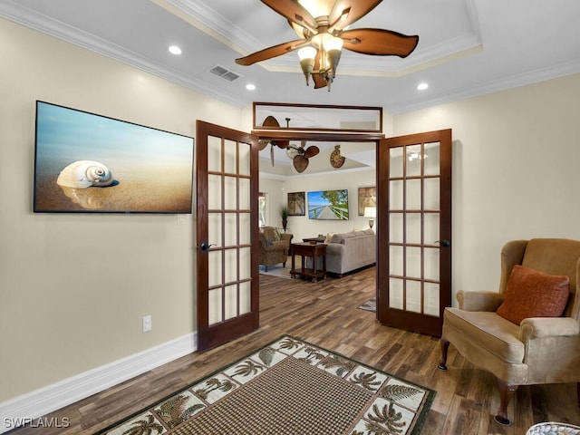 sitting room with crown molding, french doors, ceiling fan, dark hardwood / wood-style floors, and a tray ceiling