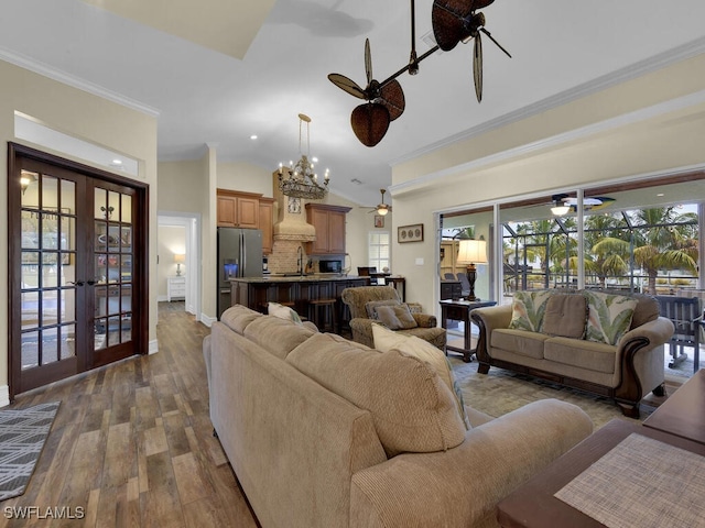 living room with crown molding, dark wood-type flooring, ceiling fan with notable chandelier, and french doors