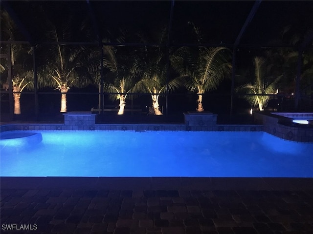 pool at night with an in ground hot tub