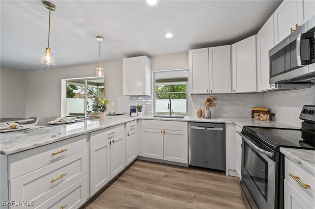 kitchen with appliances with stainless steel finishes, white cabinets, hanging light fixtures, and sink