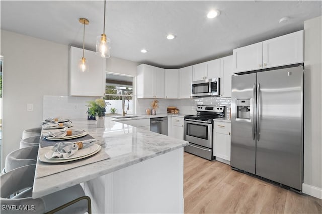 kitchen with light stone countertops, white cabinets, appliances with stainless steel finishes, and sink