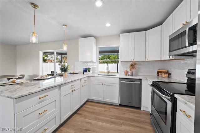 kitchen with decorative light fixtures, white cabinets, sink, and stainless steel appliances