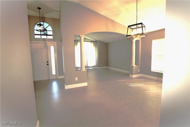 foyer entrance featuring decorative columns and high vaulted ceiling