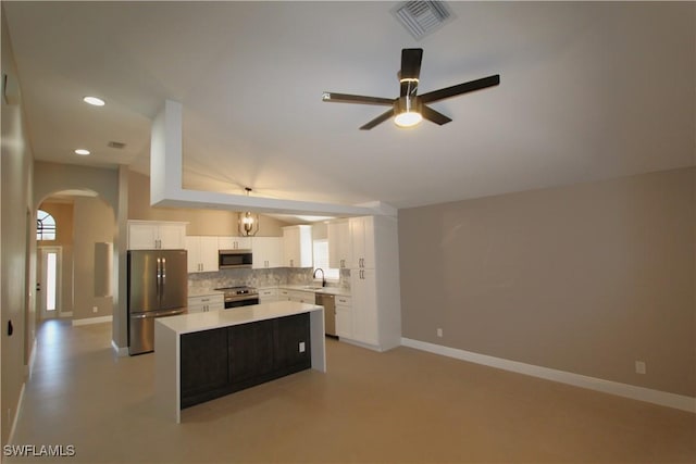 kitchen featuring backsplash, stainless steel appliances, a kitchen island, sink, and white cabinetry